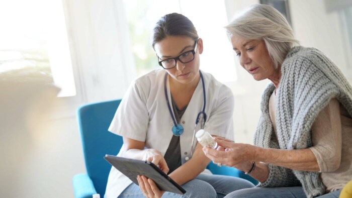 Elderly patient and healthcare professional looking at a tablet