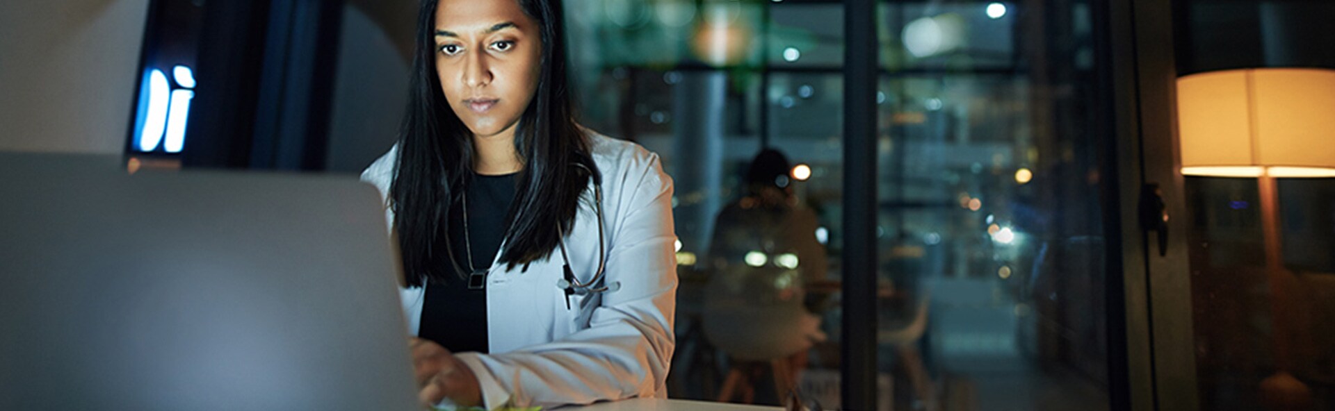 A woman in labcoat looking at a laptop